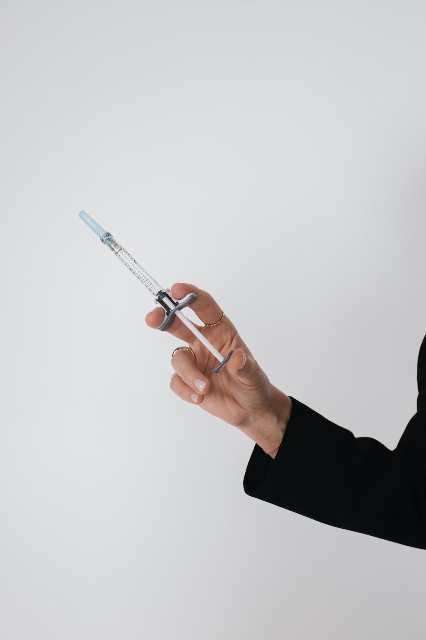 Aesthetic syringe held against a clean neutral background